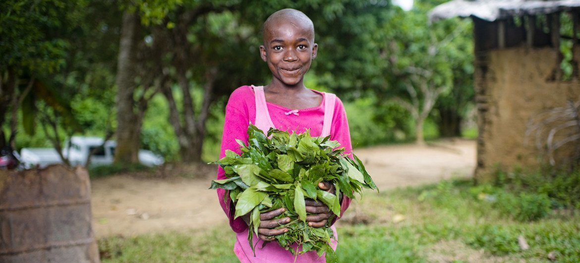 CIFOR/Ollivier Girard A child holds vegetables grown in her garden in a village in Cameroon.