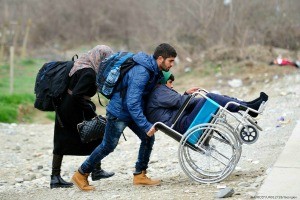 Image of a man pushing a family member in a wheelchair. Photo Credits: UNICEF/UN012728/Georgiev