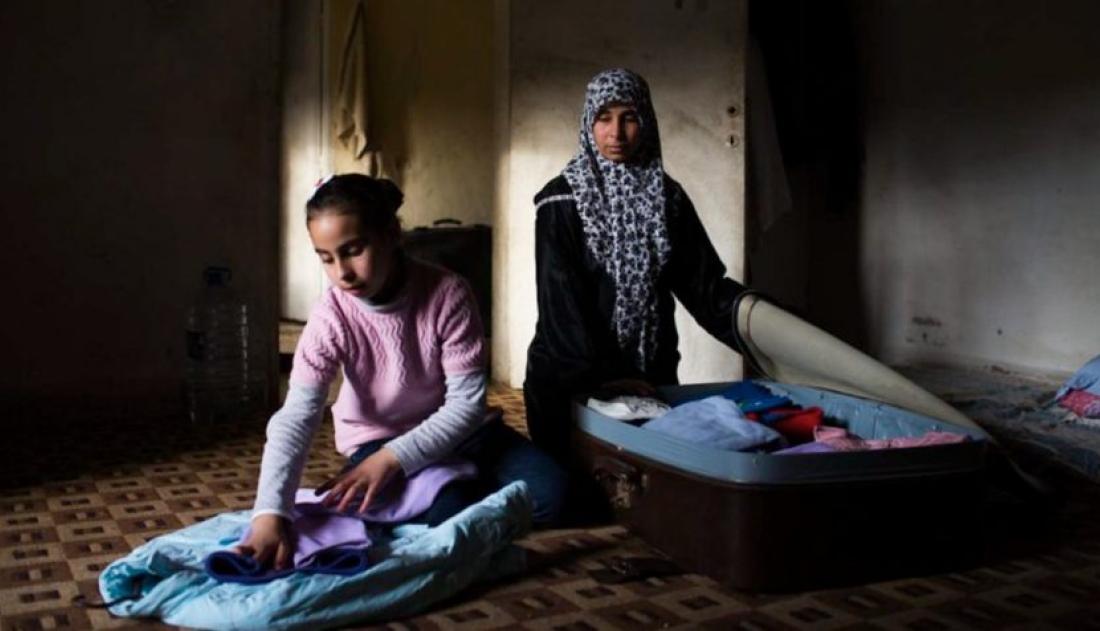 A mother wearing a burqa and her daughter packing bags