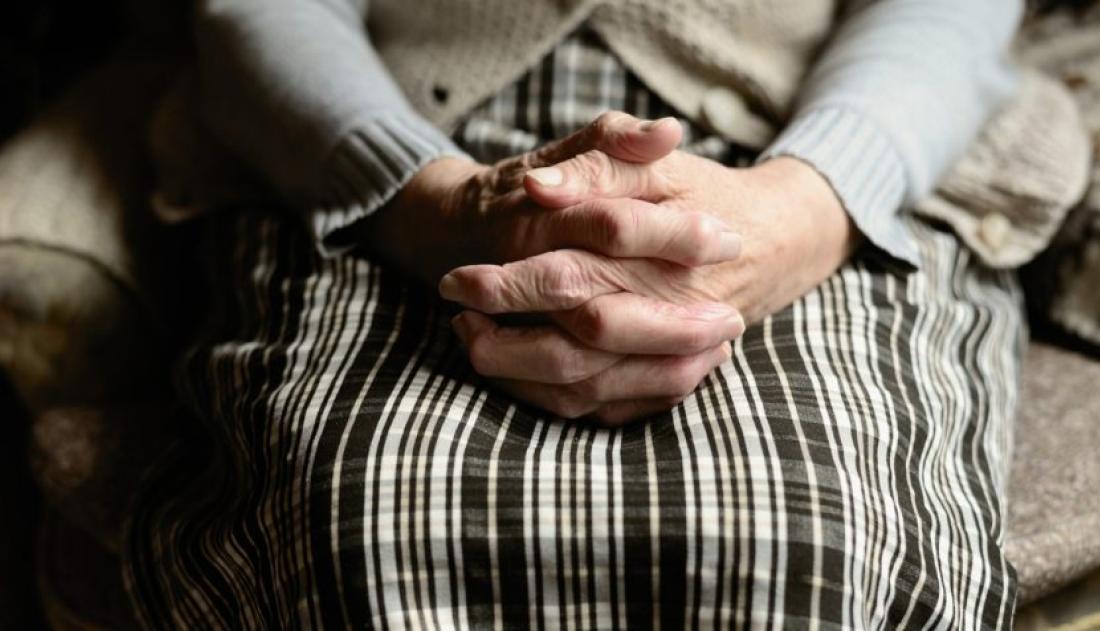 Old Woman sitting with her hands on her laps