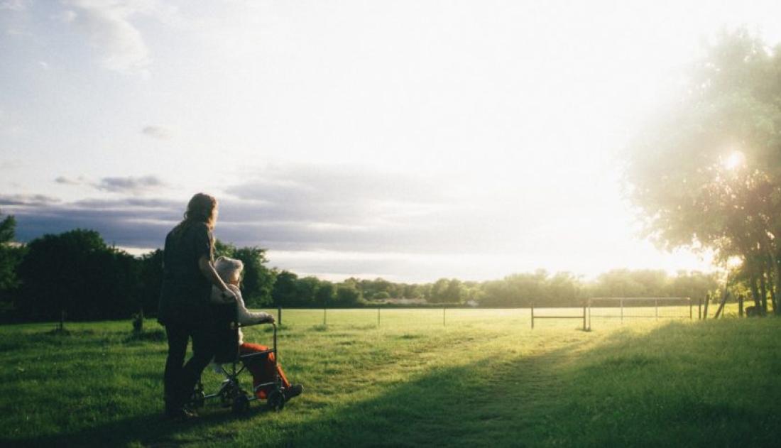 Elderly persons looking at the Sun set. One is in a wheel chair