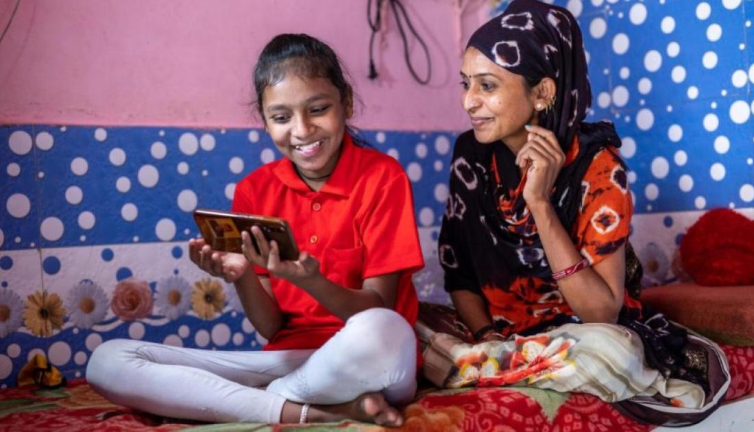 A mother and her daughter looking a smartphone
