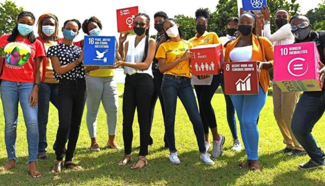 A group og young people wearing masks and holding UN Development Goals symbols